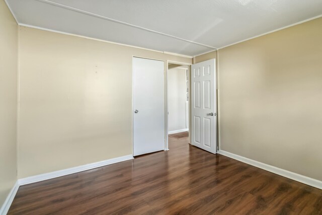 empty room featuring dark wood-style floors and baseboards