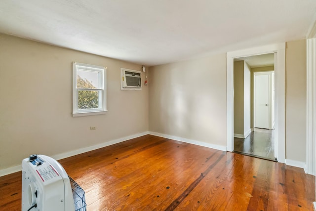 spare room featuring an AC wall unit, wood finished floors, and baseboards