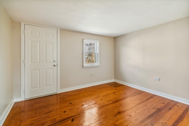 spare room with baseboards and wood finished floors