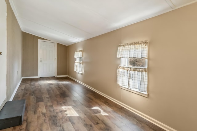 spare room with lofted ceiling, dark wood-type flooring, and baseboards