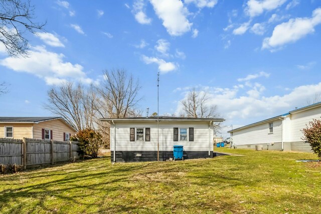 back of property featuring a lawn and fence