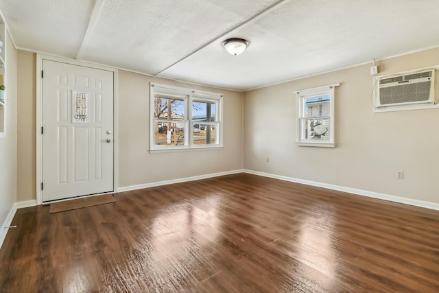 foyer entrance with dark wood-style floors, a wall unit AC, and baseboards