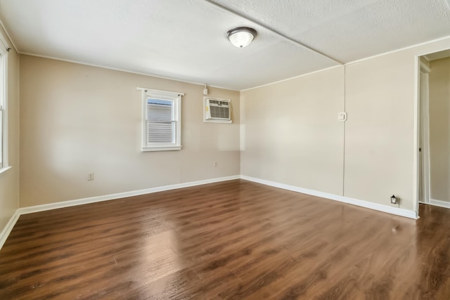 unfurnished room with a textured ceiling, a wall mounted AC, dark wood finished floors, and baseboards