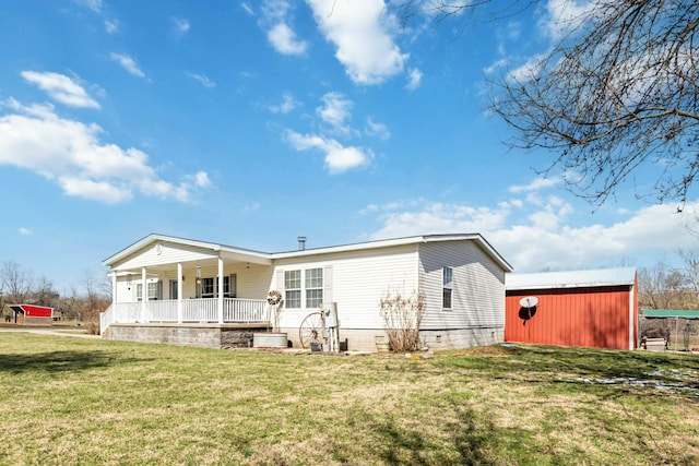 rear view of house with covered porch, an outdoor structure, and a yard