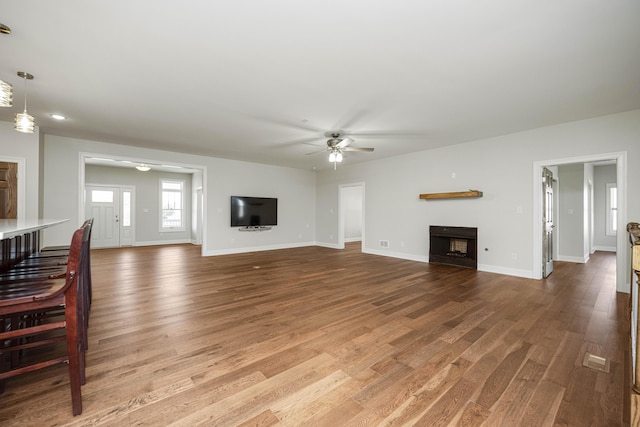 living area with light wood-style flooring, a fireplace, baseboards, and ceiling fan