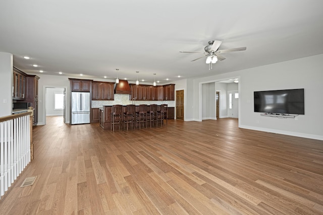 unfurnished living room with visible vents, baseboards, a ceiling fan, light wood-style floors, and recessed lighting