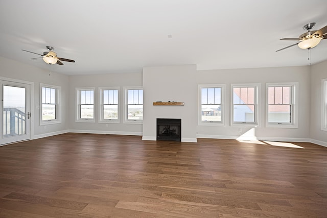 unfurnished living room featuring ceiling fan, dark wood-style flooring, a fireplace, and baseboards