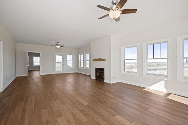 unfurnished living room featuring ceiling fan, a fireplace, wood finished floors, and baseboards