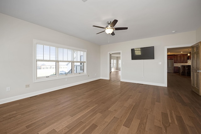 unfurnished living room featuring baseboards, visible vents, ceiling fan, and dark wood-type flooring