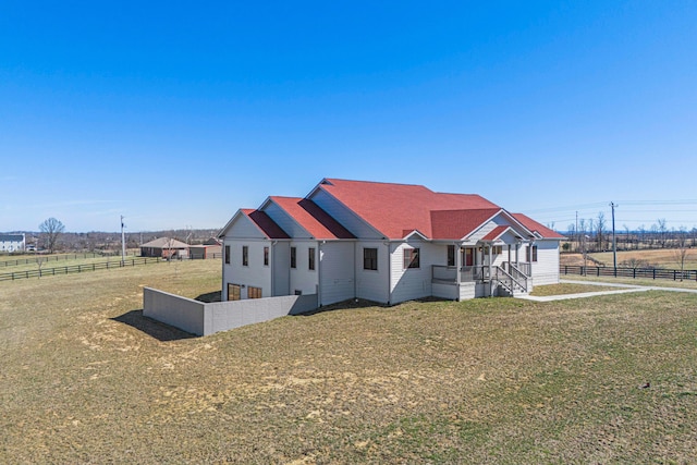 view of front facade with a front yard, a rural view, and fence