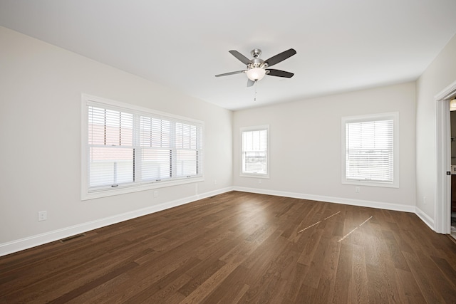 unfurnished room with dark wood-type flooring, visible vents, baseboards, and a ceiling fan