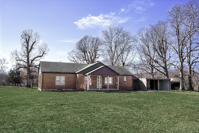 view of front of house with a front yard, a chimney, a porch, and brick siding