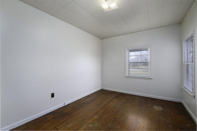 spare room featuring dark wood-style floors and baseboards