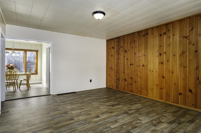 spare room with wood walls, dark wood finished floors, and baseboards