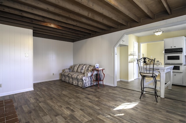 living room with beamed ceiling, arched walkways, baseboards, and dark wood finished floors