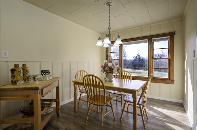 dining space with ornamental molding, dark wood-style floors, an inviting chandelier, and a decorative wall