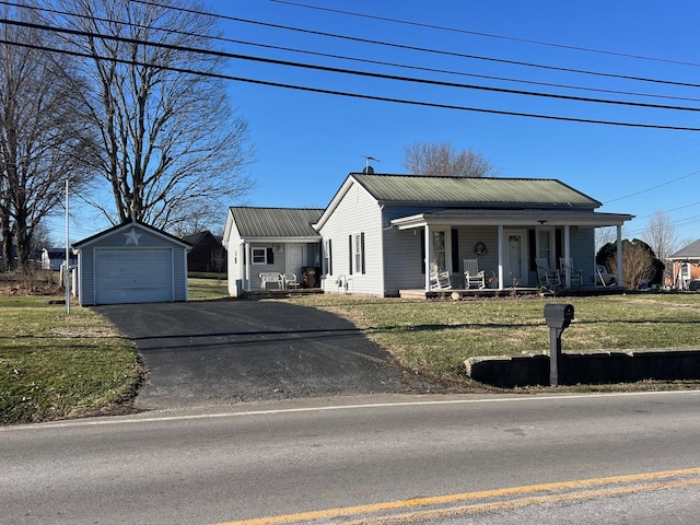 view of front of home with an outbuilding, a porch, a front yard, metal roof, and driveway