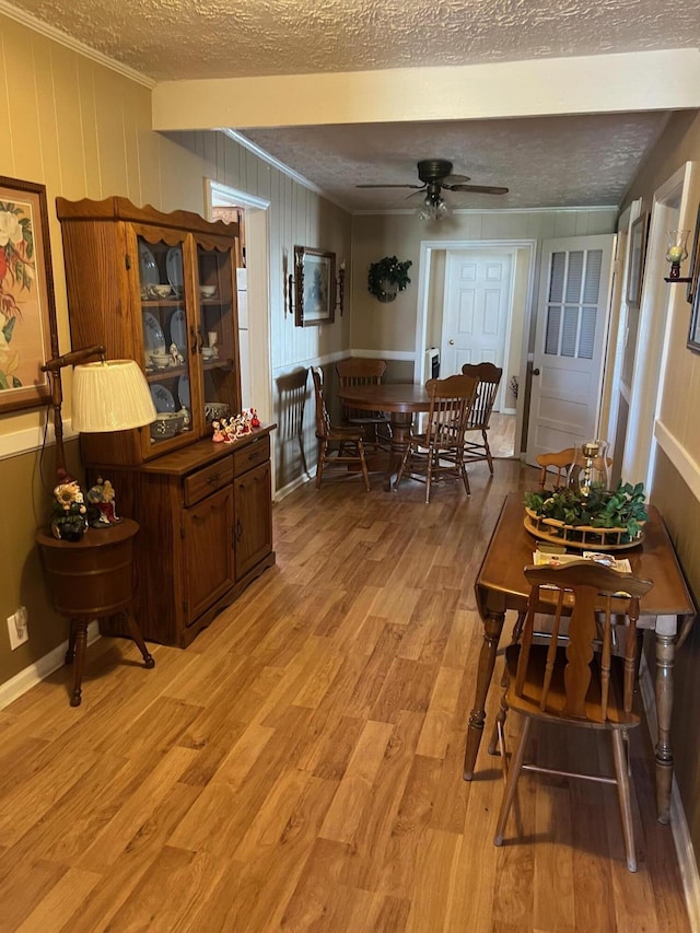 dining room with a textured ceiling, a ceiling fan, light wood-style flooring, and crown molding