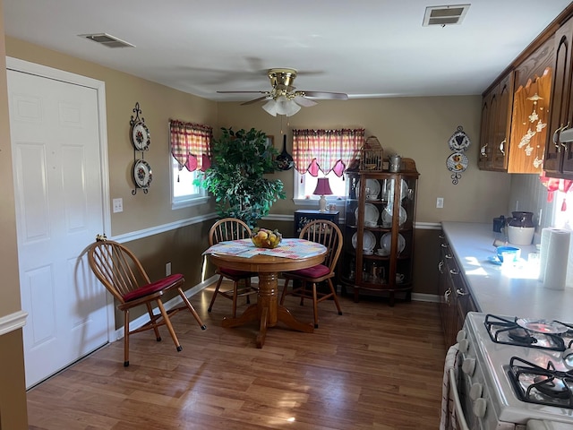 dining space with a ceiling fan, visible vents, and wood finished floors