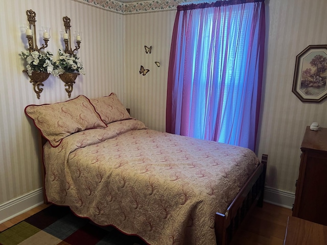 bedroom with wallpapered walls, baseboards, and wood finished floors