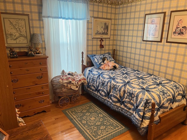 bedroom with wood finished floors and wallpapered walls