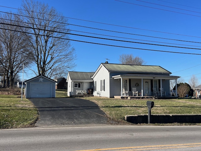 view of front of home featuring an outbuilding, metal roof, a porch, aphalt driveway, and a front lawn