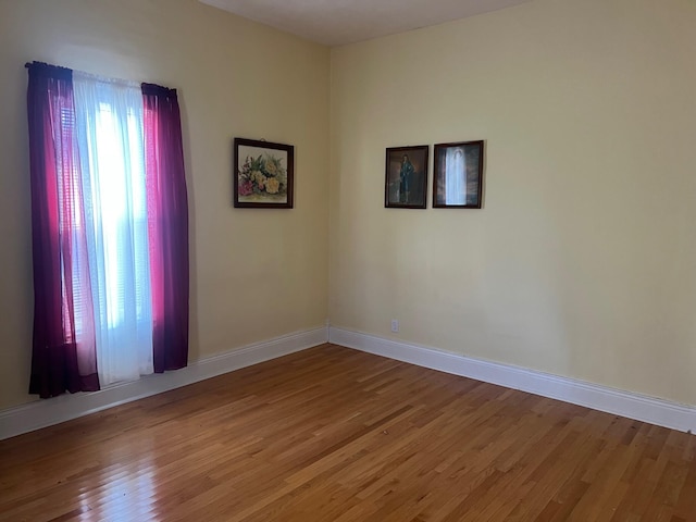 spare room with baseboards and wood finished floors