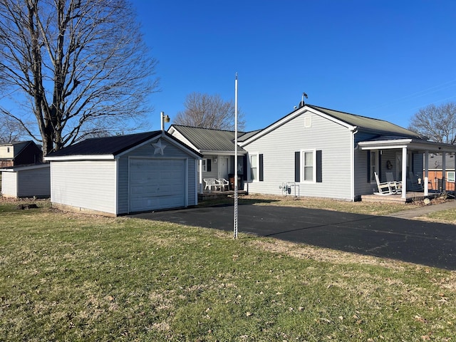 view of home's exterior with a garage, a lawn, metal roof, aphalt driveway, and a porch