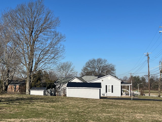 exterior space with a shed, metal roof, a lawn, and an outdoor structure