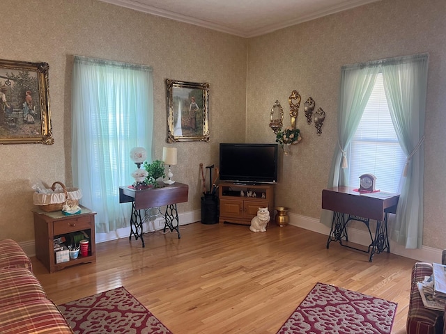 living area with wallpapered walls, baseboards, ornamental molding, and wood finished floors