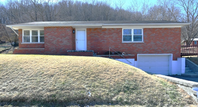 single story home with an attached garage, a front yard, and brick siding