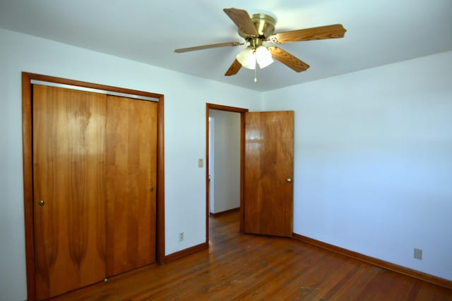 unfurnished bedroom with dark wood-style floors, a closet, a ceiling fan, and baseboards