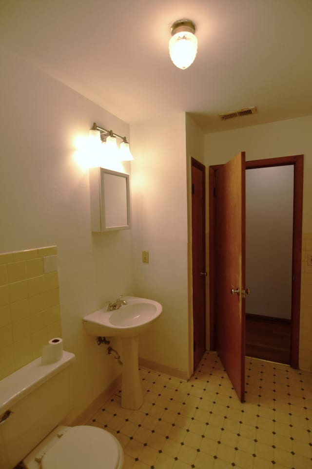 half bath with toilet, baseboards, and visible vents