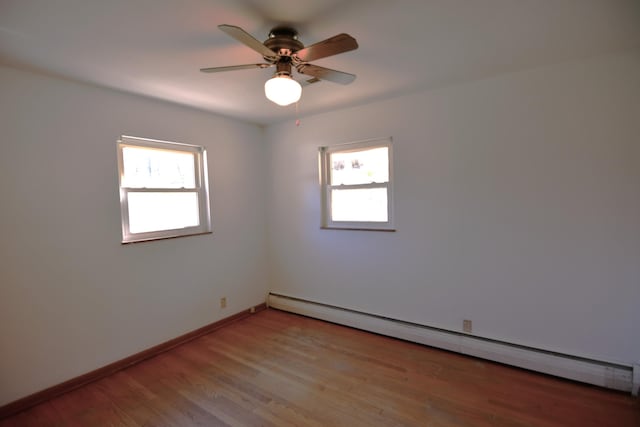 empty room with light wood-type flooring, a baseboard radiator, baseboards, and a wealth of natural light