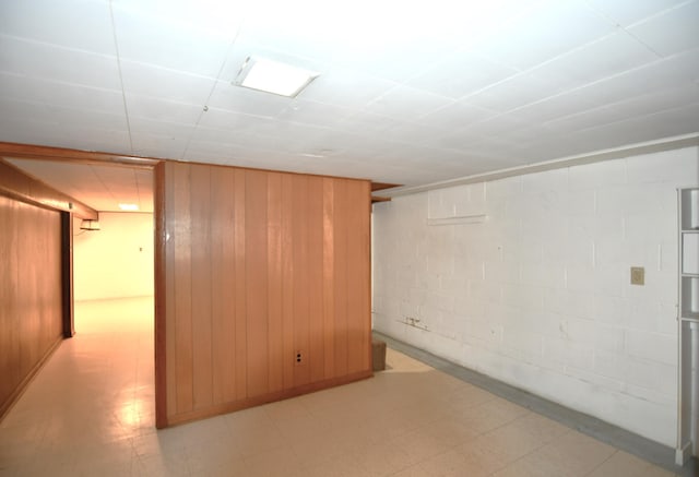 finished basement featuring light floors, wood walls, and concrete block wall