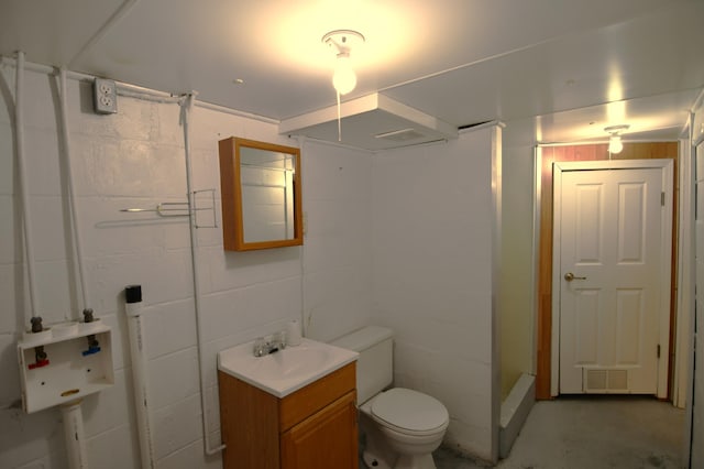 full bath with concrete block wall, visible vents, toilet, unfinished concrete floors, and vanity