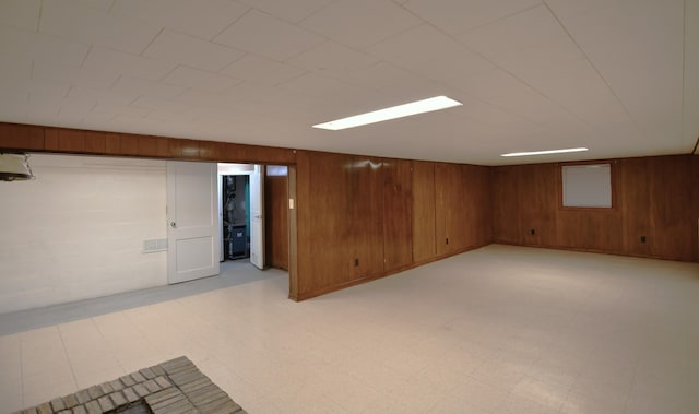 finished basement featuring light floors and wood walls