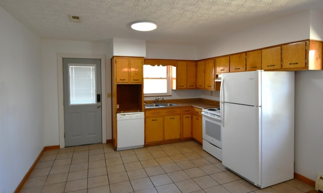 kitchen with white appliances, brown cabinetry, a sink, and light tile patterned flooring