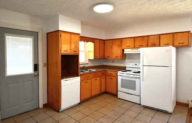 kitchen with brown cabinetry, white appliances, a sink, and under cabinet range hood