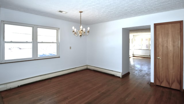 spare room featuring a textured ceiling, baseboard heating, dark wood-style floors, and visible vents