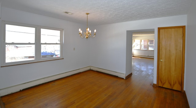 empty room with visible vents, dark wood-style flooring, an inviting chandelier, a textured ceiling, and a baseboard heating unit