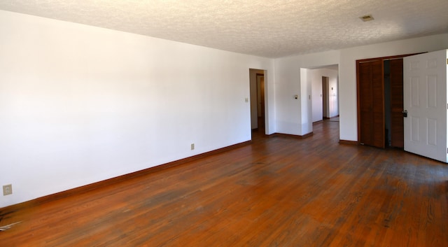 unfurnished bedroom featuring a textured ceiling, a closet, baseboards, and dark wood-style flooring