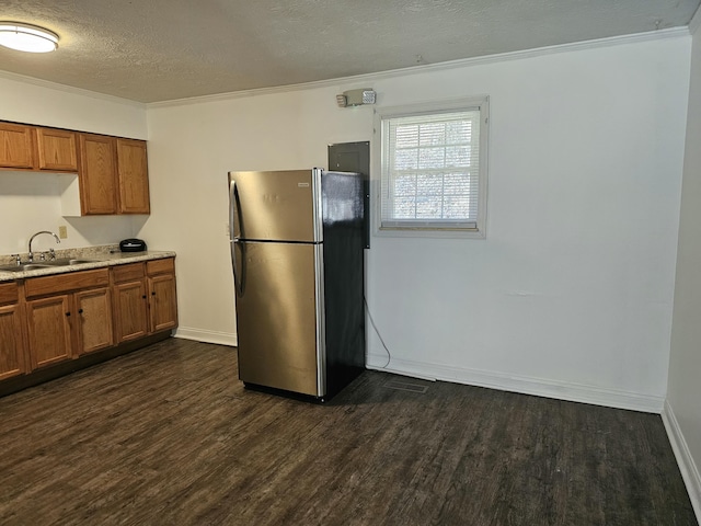 kitchen featuring freestanding refrigerator, dark wood finished floors, brown cabinets, and a sink