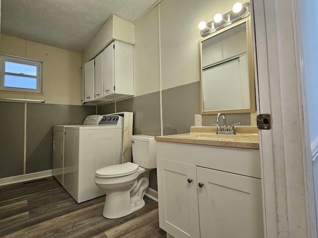 bathroom featuring toilet, wood finished floors, washing machine and clothes dryer, a textured ceiling, and vanity