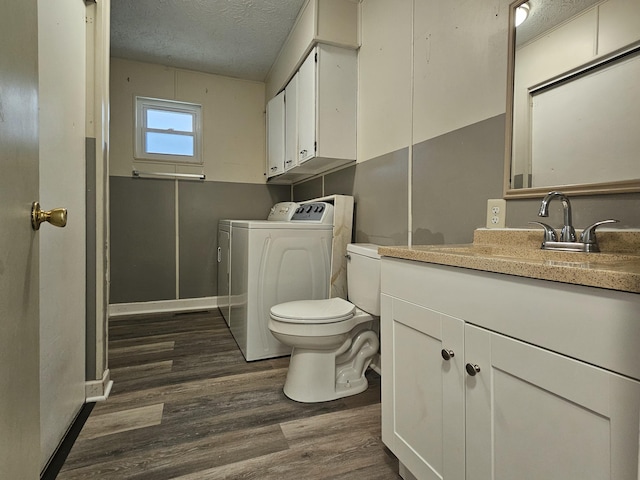 bathroom featuring a textured ceiling, washing machine and dryer, toilet, wood finished floors, and baseboards