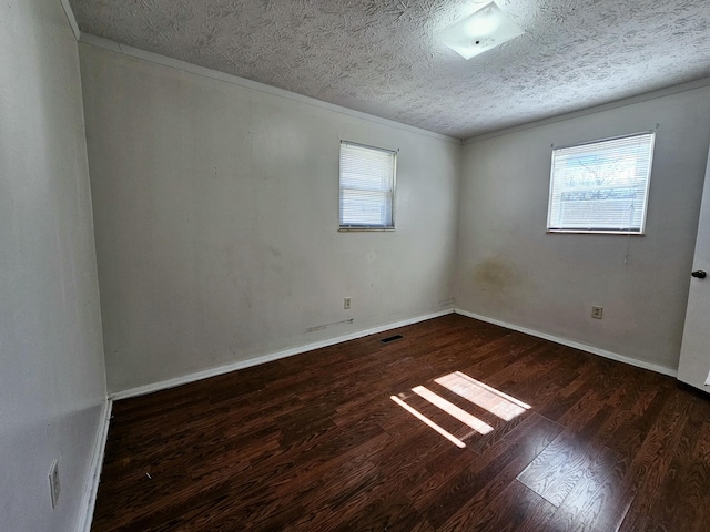 empty room with plenty of natural light, a textured ceiling, and wood finished floors