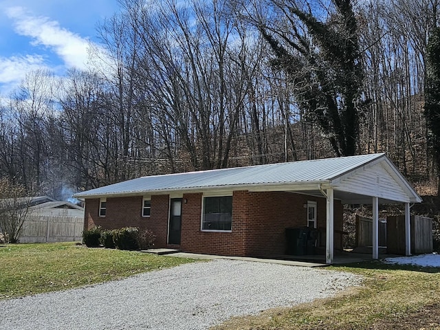 ranch-style house with metal roof, brick siding, fence, driveway, and a front yard