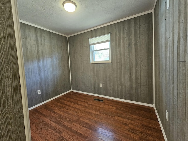 empty room featuring visible vents, a textured ceiling, baseboards, and wood finished floors