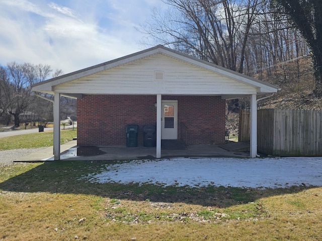 view of side of home featuring brick siding, fence, and a lawn