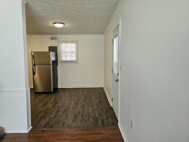 interior space featuring wainscoting, a textured ceiling, dark wood-type flooring, and freestanding refrigerator